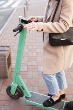 Elektrikli scooter 'a binen bir kadının dikey kesikli görüntüsü.