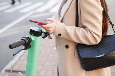 Mobil uygulama üzerinden elektrikli scooter kiralayan tanınmayan bir kadın.