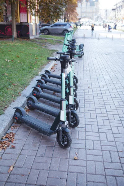 街の通りに並ぶレンタル電動スクーターの垂直ショット — ストック写真