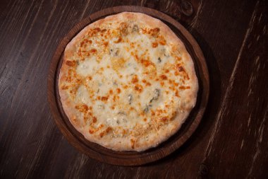 Top view shot of delicious quattro formaggi pizza on a wooden table