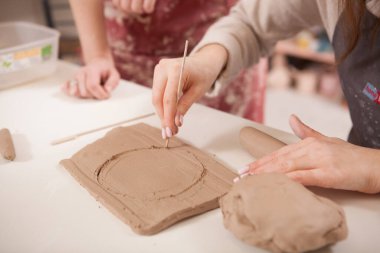 Çemberi balçıktan kesen bir kadının yakın çekimi.