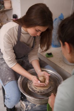 Bir kadının çömlekçiden çömlekçi tenceresi fırlatmayı öğrenirken dikey görüntüsü.