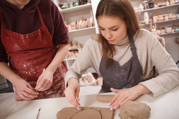 陶瓷课上 漂亮的年轻女子从一块粘土上切下圆圈 — 图库照片