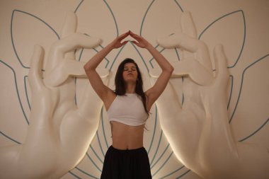 Güzel genç bir kadın enerji egzersizi yapıyor, yoga dersinde dans ediyor.