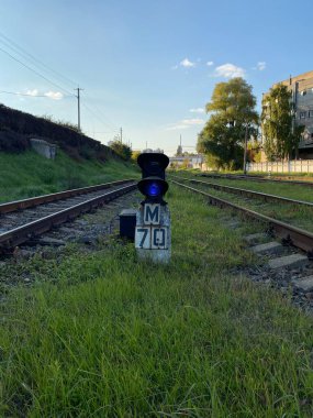 Mavi gökyüzünün altındaki çimlerde mavi tren yolu trafik ışığı