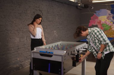 Genç çift randevuda masa futbolu oynuyor.