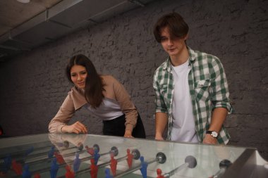 Yakışıklı genç adam ve kız arkadaşı masa futbolundan zevk alıyorlar.