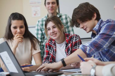 Çalışırken gülümseyen ve konuşan mutlu öğrenciler.