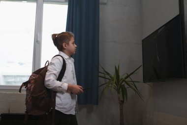 Okul çocuğu sırt çantası takıyor, sabahları televizyon izliyor.