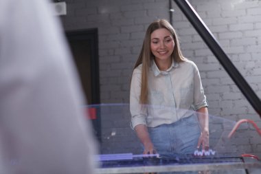 Güzel kadın gülüyor, hava hokeyi oynuyor.