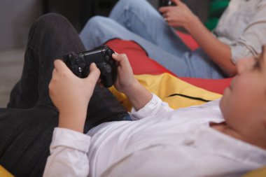 Oyun oynayan, elinde joystick olan bir çocuğun kırpılmış görüntüsü.