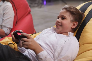 Elinde bir konsolla video oyunu oynayan mutlu çocuk.