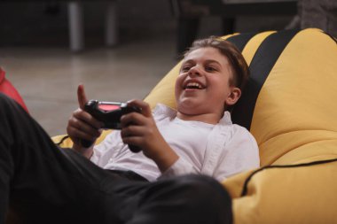 Küçük çocuk gülüyor, video oyunları oynuyor, konsol tutuyor.