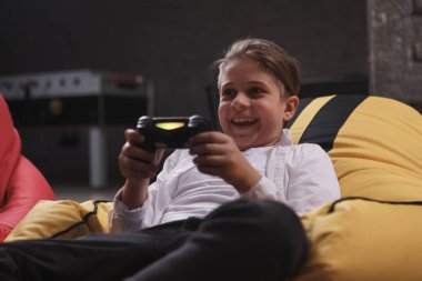 Heyecanlı genç çocuk bağırıyor, konsol kullanarak video oyunları oynuyor