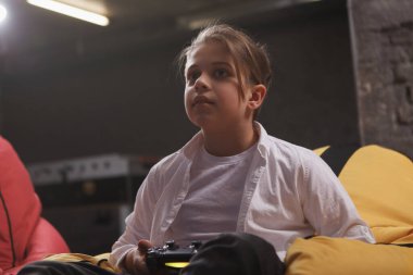 Konsantre olmuş video oyunları oynayan küçük bir çocuğun düşük açılı çekimi.
