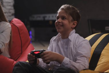 Mutlu çocuk gülümsüyor, kumanda kolu tutuyor, video oyunları oynuyor.