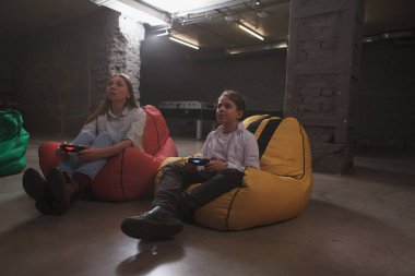 Anne ve oğlu otelin oyun odasında eğleniyor, oyun konsolları kullanıyor, video oyunları oynuyorlar.