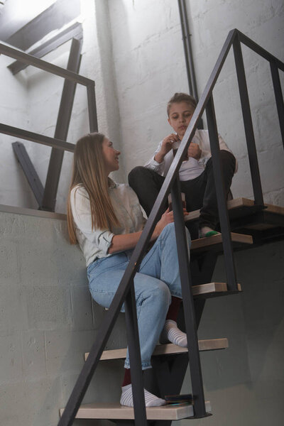 Vertical shot of a mother and son sitting on the stairs inside their modern loft apartment
