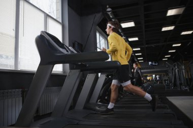 Koşu bandında koşan atletik bir adamın tam boy kardiyo çalışması.