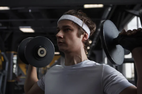 Close up of a fitness man wearing headband during dumbbell workout