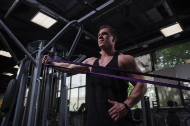 Low angle shot of a sportsman using resistance rubber band at the gym