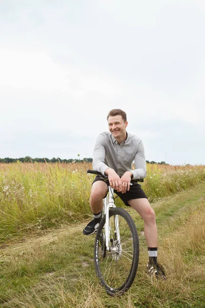 Handsome man is smiling while cycling in the field
