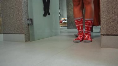 Genç kızların bacakları Noel çoraplarıyla odaya giriyor ve yerde yürüyor.