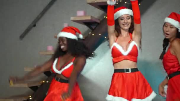 三个身穿红色新年服装的欧洲 亚洲和非洲小女孩在圣诞树前跳着帽舞 面带微笑 — 图库视频影像