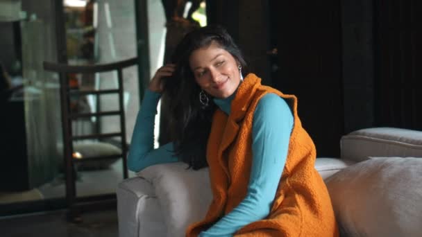 아름다운 소녀가 소파에 스웨터를 웃으며 내다본다 — 비디오