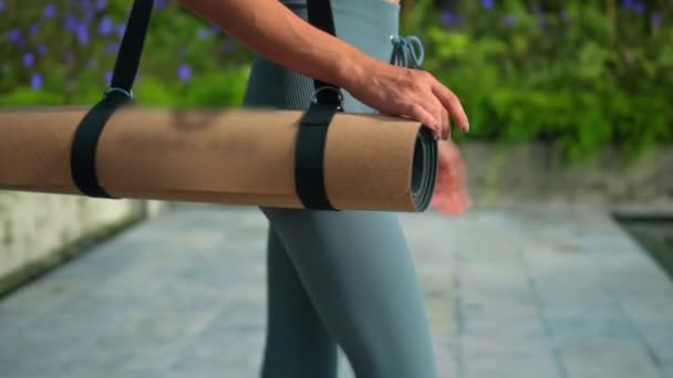 一位年轻迷人的欧洲黑发女运动员带着一块瑜伽毯 带着绿色的热带雨林 在游泳池边明亮的背景下 — 图库视频影像