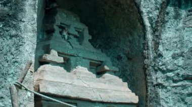 Bir maymun taş bir kasabada taş bir kapıda oturur ve meyve yer.