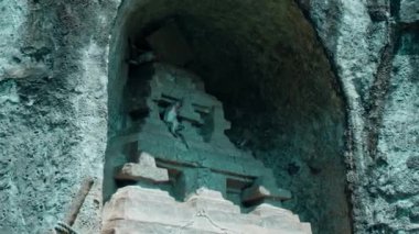 Bir maymun taş bir kasabada taş bir kapıda oturur ve meyve yer.