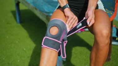 Genç Avrupalı sporcu kız dizindeki koruyucu bandı dizine takıyor ve diz sakatlığı geçiriyor.