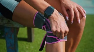 Genç Avrupalı sporcu kız dizindeki koruyucu bandı dizine takıyor ve diz sakatlığı geçiriyor.