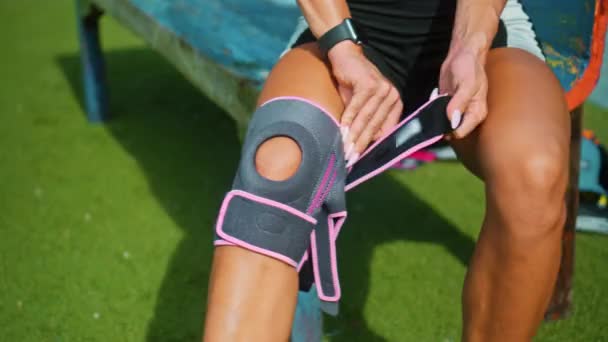 由于膝伤 年轻的欧洲女运动员将双手放在膝盖上的防护带上 — 图库视频影像