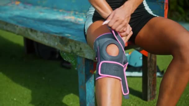 Joven Atleta Europea Pone Sus Manos Una Banda Protectora Rodilla — Vídeo de stock