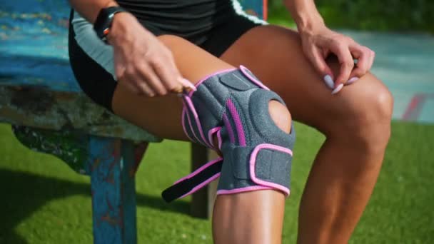 由于膝伤 年轻的欧洲女运动员将双手放在膝盖上的防护带上 — 图库视频影像
