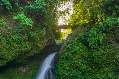 Şelalenin taş geçitleri arasında parlayan sabah güneşinin görüntüsü.