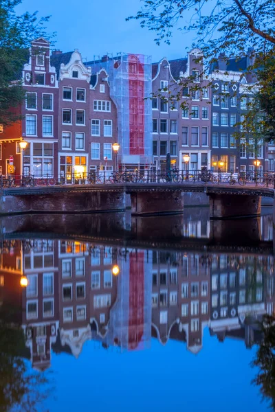 オランダだ アムステルダムの早朝 運河の水の中に駐車自転車や伝統的な家の反射と橋 — ストック写真