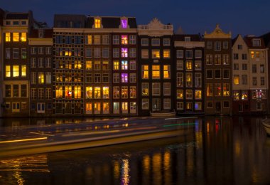 Hollanda 'da. Geceleri Amsterdam 'da klasik kanal evleri ve hareketli bir tekne.