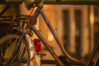 Hollanda 'da. Amsterdam rıhtımında bir gece. Çitin yanındaki paslı eski bisiklet Bir fenerin ışığında Örümcek ağı ve bir örümcekle
