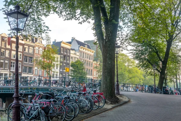 Hollanda 'da. Amsterdam kanalında sabah. Köprü ve setin üzerine bir sürü bisiklet park edilmiş.