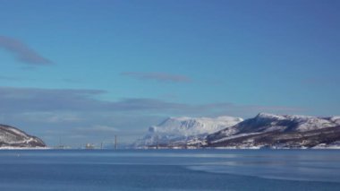 Norveç fiyordunun üzerinde kış güneşli bir gün. Karla kaplı dağlar ve yol köprüsü. Hızlı hareket