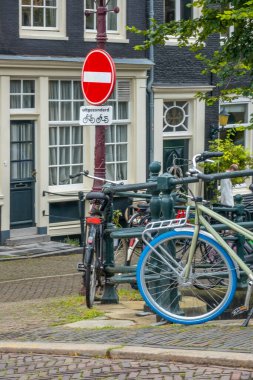 Netherlands. Amsterdam canal promenade with traditional houses and parked bicycles. Under the prohibition sign there is a sign in Dutch 