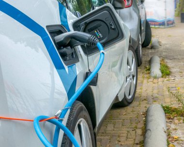 Elektrikli araba tümsek durağının yanında park halinde. Bağlı kablo yakın plan
