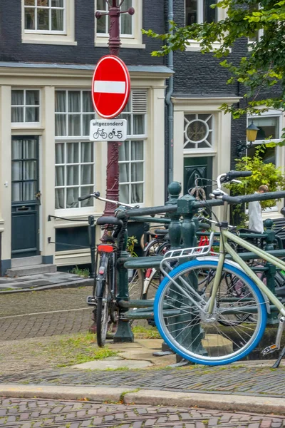 Hollanda 'da. Geleneksel evler ve park edilmiş bisikletlerle Amsterdam Kanal Alanı. İçki yasağı tabelasının altında Hollandaca bir işaret var.