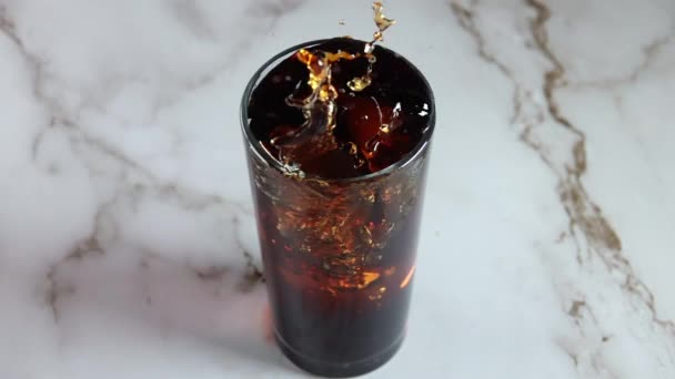 Glas Mit Cola Auf Einem Marmortisch Der Eiswürfel Fällt Die — Stockvideo