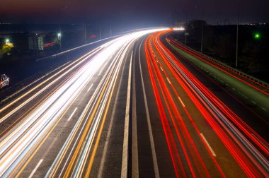 Geceleri banliyö otoyolu. Farlardan ve trafik ışıklarından izler.