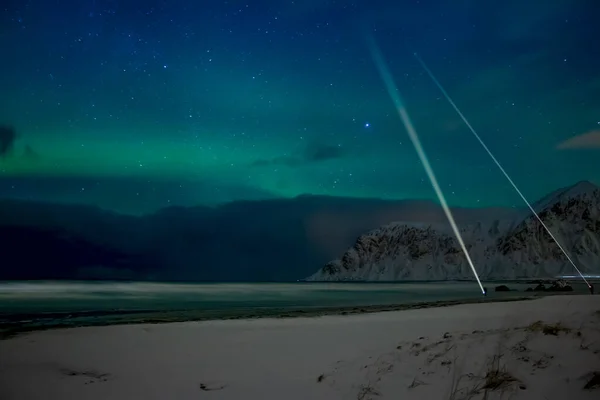 冬のノルウェー ロフトテンの山の間の夜のビーチ 懐中電灯のある光の北の光と人々 — ストック写真