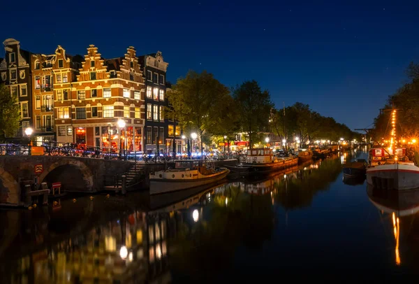 オランダだ アムステルダムと雲一つない空の夜の運河 住宅用のバージやボートは水面に反射して係留されています — ストック写真